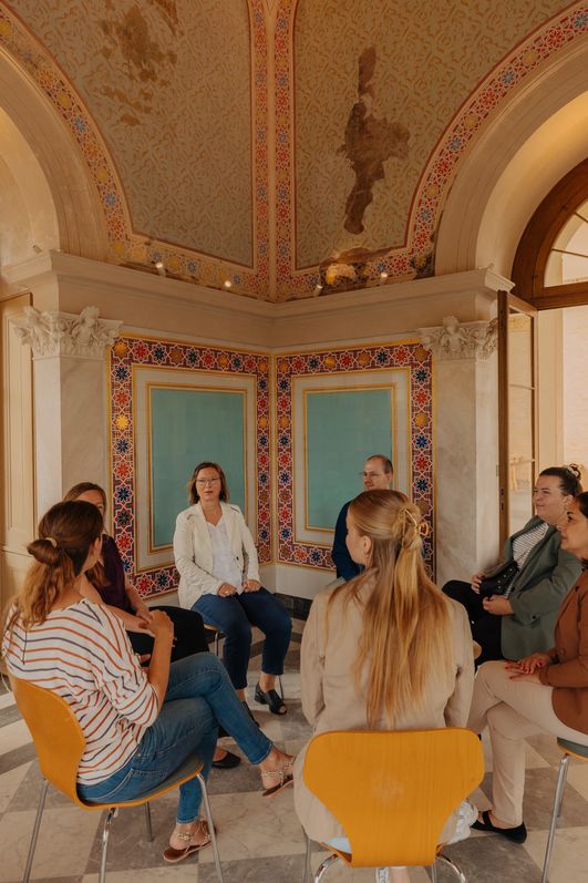 Besprechungsrunde im prunkvollen Saal des Belvedere Pfingstberg mit offenen Arkadentüren