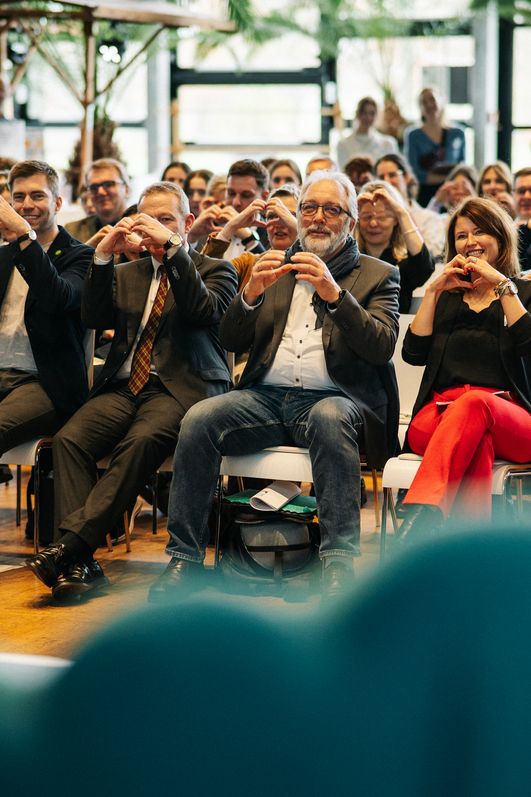 Das Publikum macht Herz-Zeichen mit den Händen in Reaktion auf die Sprecher