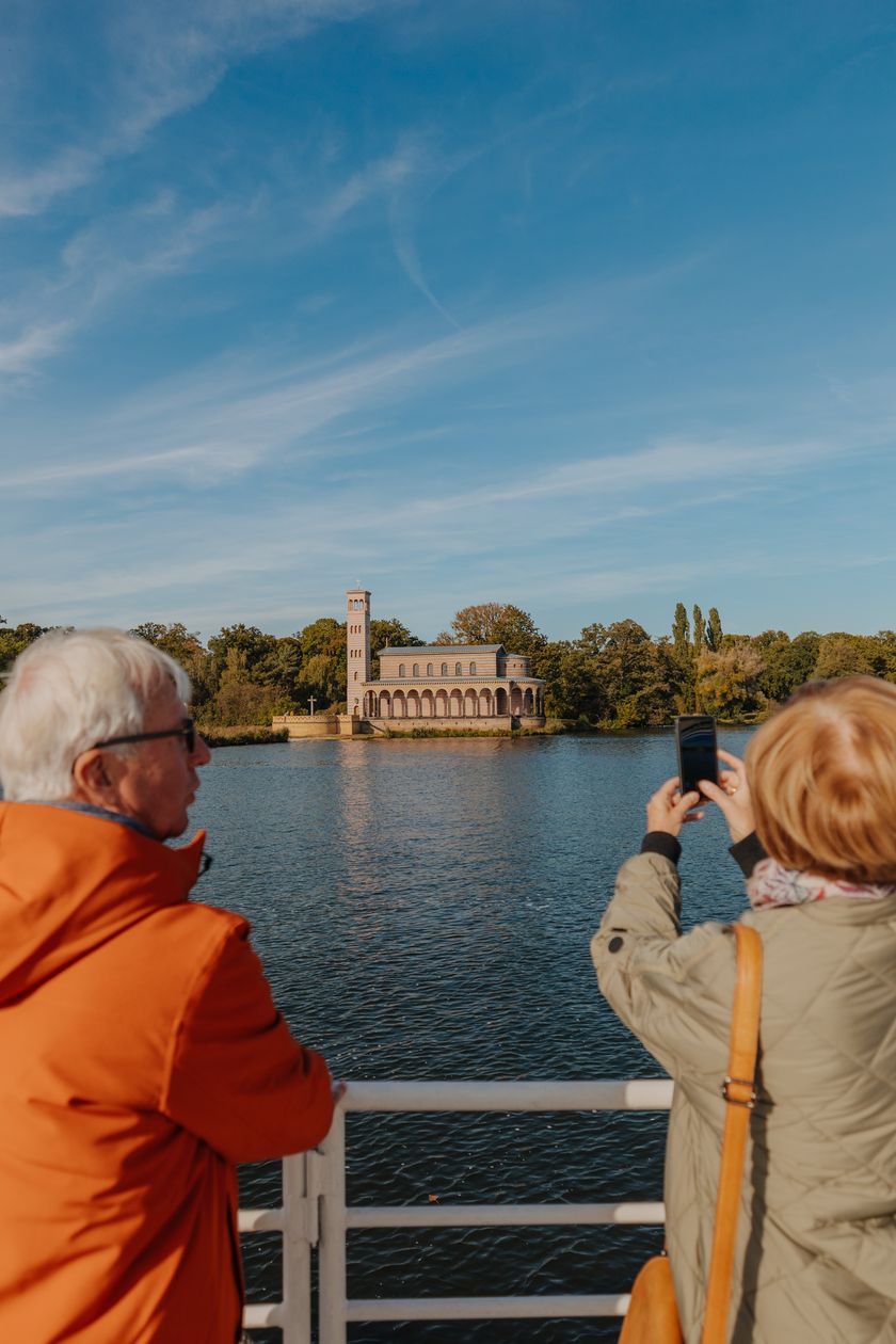 Two people are looking at the Church of the Redeemer in Sacrow from a ship of the White Fleet.