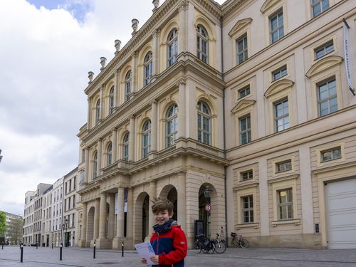 Ein Junge steht vor dem Museum Barberini mit einem Rätselheft in der Hand.