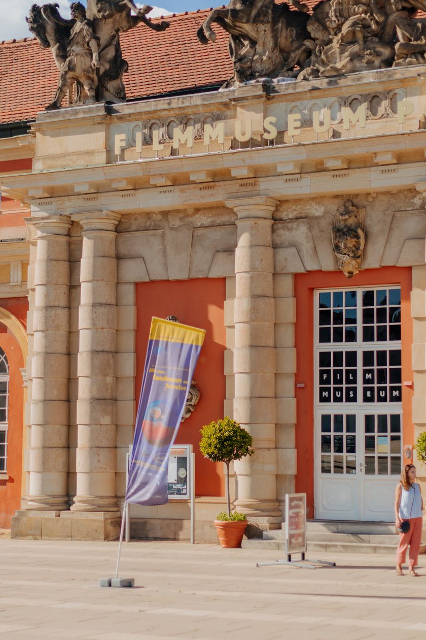 Two women are standing in front of the entrance to the film museum in summer.