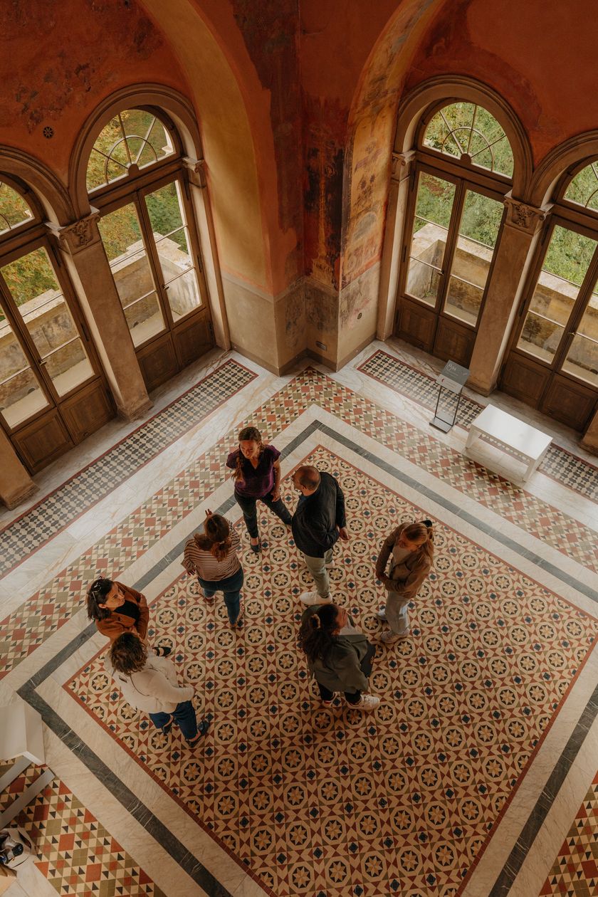 Gruppe im historischen Saal des Belvedere Pfingstberg mit Rundbogenfenstern und Mosaikboden